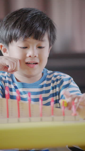 A little boy playing with a colorful abacus in the living room at home.