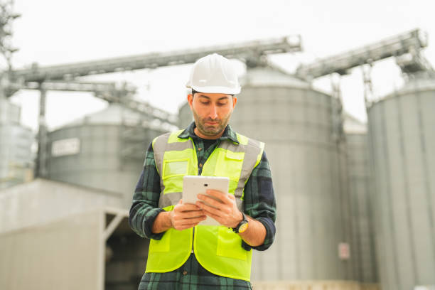 istock Male engineer in front of grain warehouse in agricultural district looking at tablet 1953183249