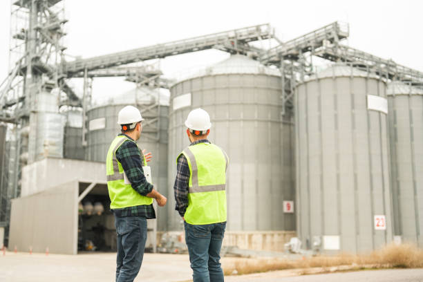 istock Two male engineers with their backs turned, standing in front of a grain warehouse in the agricultural area, are talking. agricultural production 1953206467