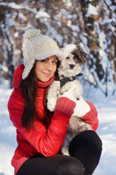 Woman hugging her havanese dog in the winter forest