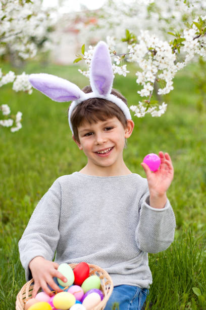istock Easter egg hunt. preschool boy wearing bunny ears collecting colorful eggs on Easter egg hunt in garden. Easter 1953224095