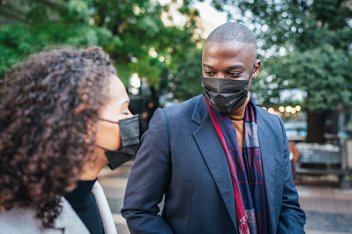Young couple walking and talking outdoor on the city street wearing face protective mask to prevent Coronavirus or anti-smog.
Portrait of a young African American couple wearing protective face masks