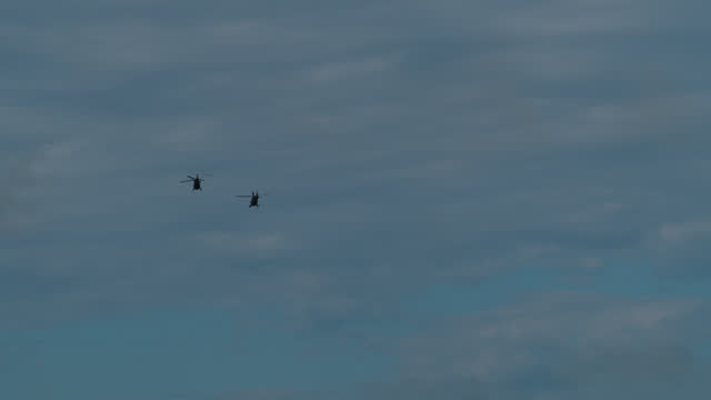 SUPER SLO MO Majestic Might: Low Angle View of Two Army Helicopters Against Cloudy Sky