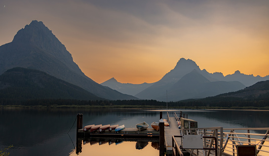 Sunset on Swiftcurrent Lake with rental boats on the dock.