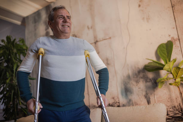 istock An elderly man walks with the help of crutches 1953275420