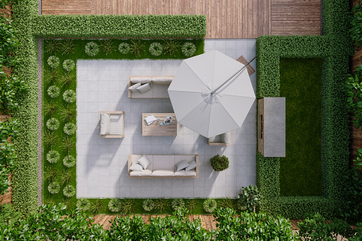 High Angle View Of Patio With Sofa, Armchairs, Coffee Table, Parasol And Bushes