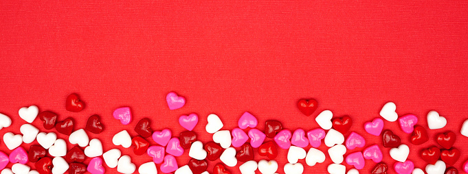 Valentines Day banner with candy hearts border over a red textured background. Overhead view with copy space.