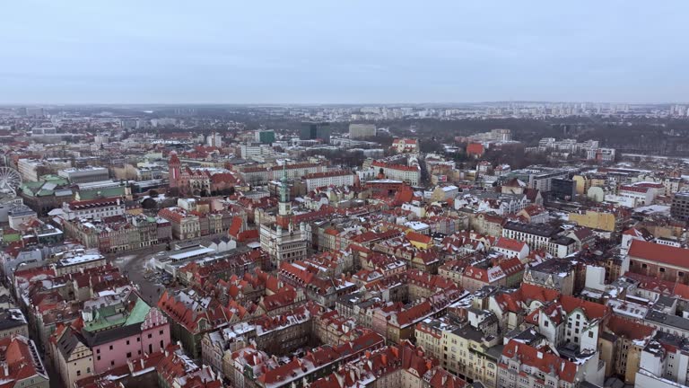 Aerial view of Poznań's historic market square in winter, showcasing the charming old townhouses adjacent to the square. The drone captures the city's architectural heritage under a daylight winter sky.