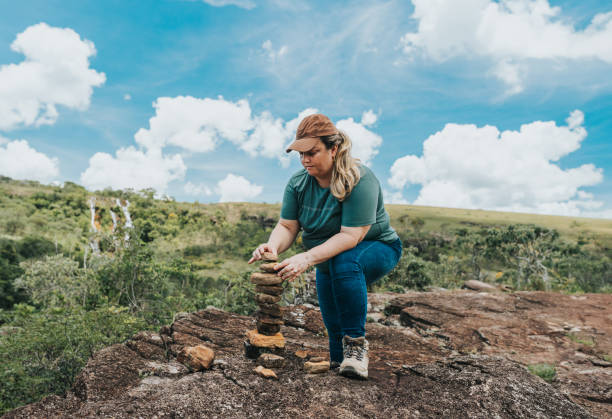 Woman stacking stones on trail in natural park, Minas Gerais, Brazil