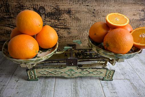 fresh oranges on the scale. top view and on wooden background, retro style.
