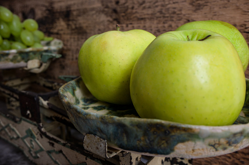 green grapes and apples on a retro scale, wooden background.