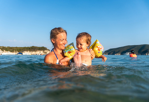 mom and baby are swimming in the sea and are happy