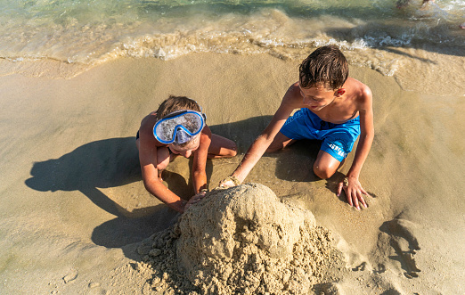 two boys are building a sand tower