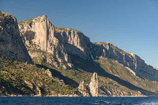 Cliffed coastline near Santa Maria Navarrese with rock pinnacle called Pedra Longa in the background in east Sardinia