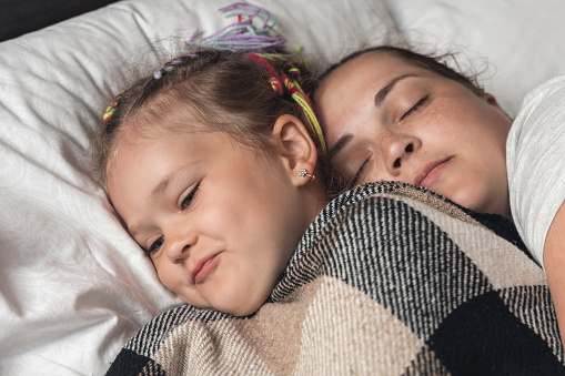 Young mother with daughter sleeping in bed.