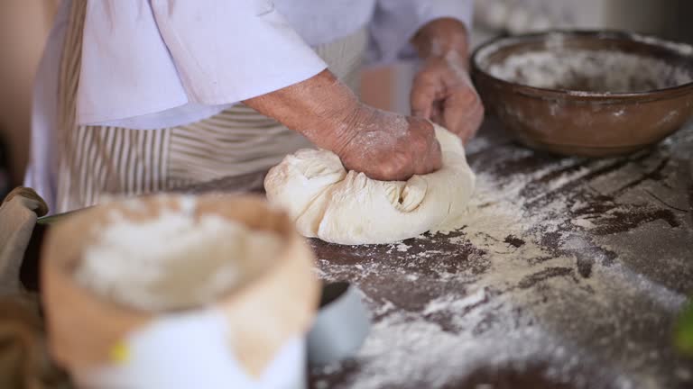 Hands, person and dough with wheat on kitchen counter for kneading bread, pizza or cake for preparation. Chef, pastry and baking or cooking process on table in restaurant, bakery or culinary cook