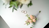 Wedding boutonniere and wedding rings on brown cloth. Wedding rings and boutonniere
