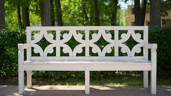 Lawn chair on white background. White bench with back in the park