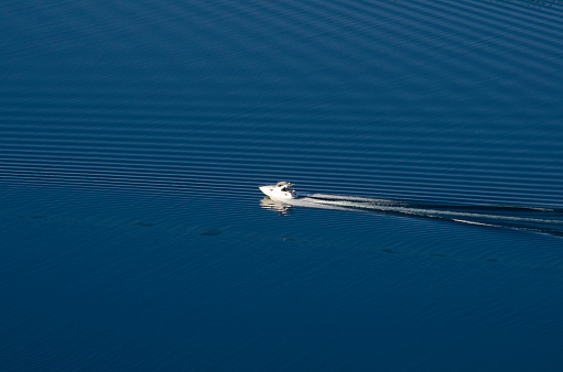 Yacht sailing on a lake with deep blue waters leaving a wake in the water. luxury vacation ride