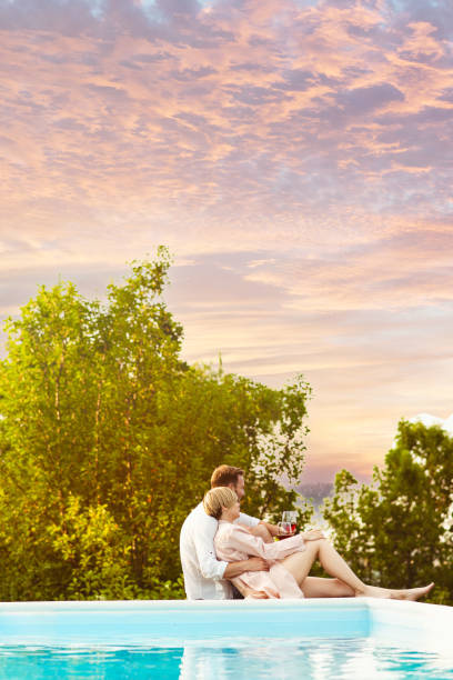 istock Couple enjoying beautiful sunset on a swimming pool 1953495619