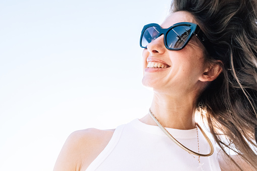 Female portrait of a woman outdoors, a luxury girl wear sunglasses. Happy person is smiling, lifestyle photography with beautiful people.