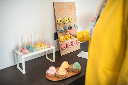 A mid adult Caucasian woman setting up a charming dessert board for a baby shower, showcasing an array of colorful treats.