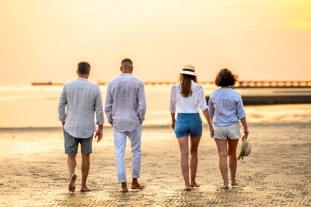 istock Friends walking along coastline at sunset 1953584651