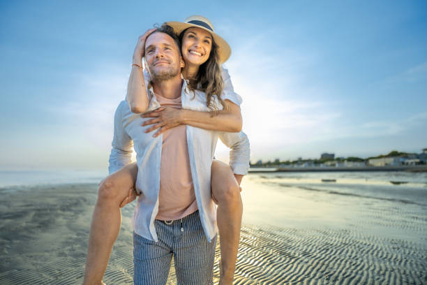 istock Couple piggyback on sand beach 1953585736