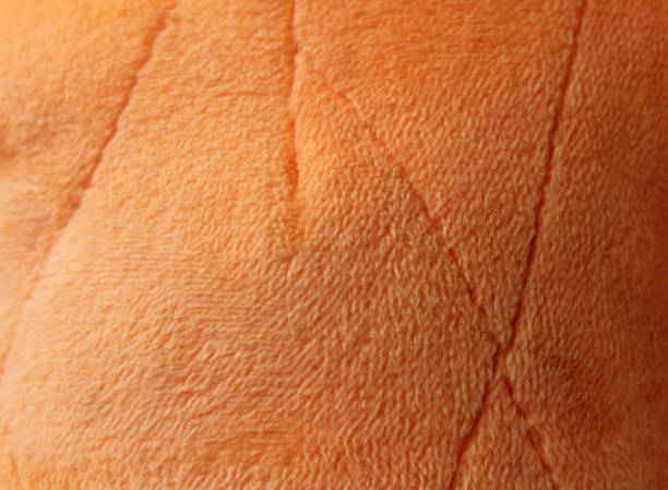 Close-up of a orange quilted velvet sofa with upholstered buttons (diamond stitching) / Rautenheftung