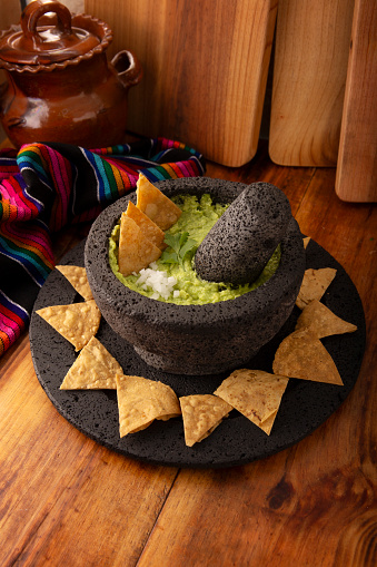 Guacamole. Avocado dip with tortilla chips also called Nachos served in a bowl made with volcanic stone mortar and pestle known as molcajete. Mexican homemade sauce recipe very popular.