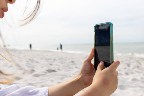 istock Woman holding cell phone on beach 1953688643