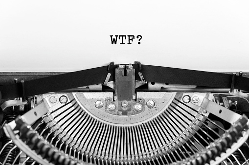 WTF what the fuck word close up being typing and centered on a sheet of paper on old vintage typewriter mechanical.