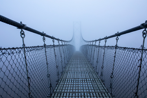 Foggy freezing winter morning, suspension bridge.