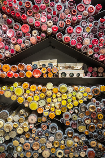 Shelves filled with stacked rolls of different warm-toned buttons.