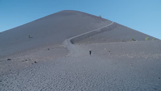 Woman hiker on Cinder Cone Trail winding up mountain in Lassen National Park