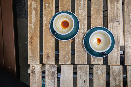 Top view of two empty blue coffee cups on saucers, sitting on a wood paneled cafe table.