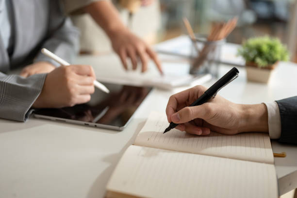 istock A businessman is taking notes on a notebook while having a meeting with his team in the office. 1953780692