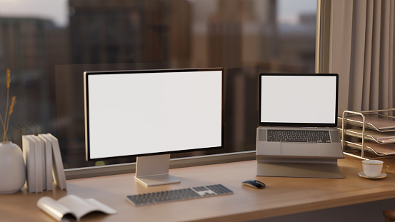 A modern office on a skyscraper with multiple computer screen, A PC and laptop computer white-screen mockup on a table against the glass window with a city skyscraper view. 3d render, 3d illustration