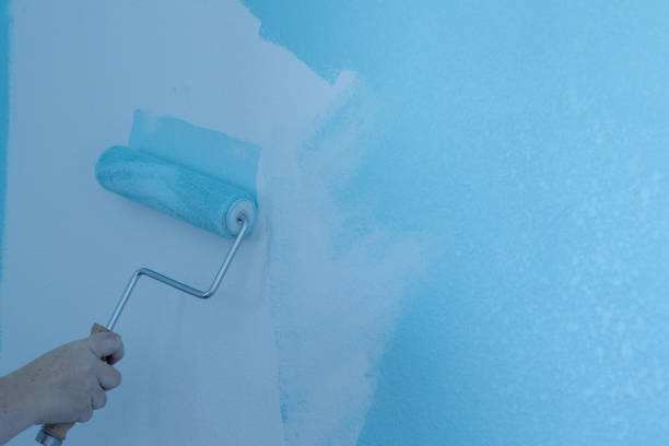 istock A hand rolling blue paint onto a white wall with a paint roller on an interior wall. 1953783820