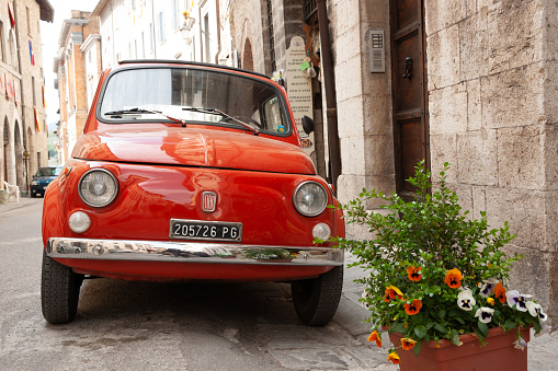 Gubbio Italy - May 13 2011; Small  red iconic Itaian car parked in traditional Italian village street.