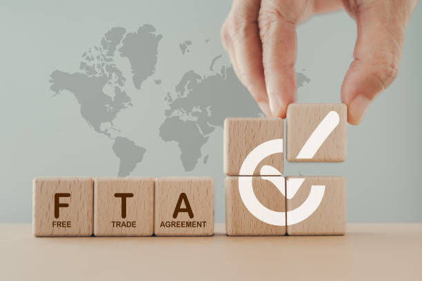 istock Hand arranged wooden cube blocks with approved signed and word FTA,  abbreviation for Free Trade Agreement, and blurred stack of coin on world map background 1953884837