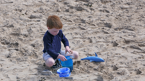 Red headed boy playing on a sandy beach in Northern Ireland Holidays in UK