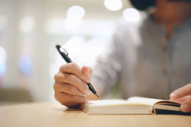 istock Close up woman hand writing on notebook at a cafe. 1953902854