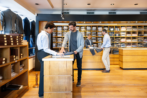 Latin American men buying clothes at a business wear store with the help of the retail clerks