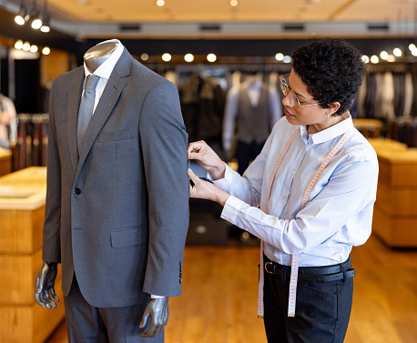 Tailor sewing a suit on a mannequin at a clothing workshop - menswear concepts