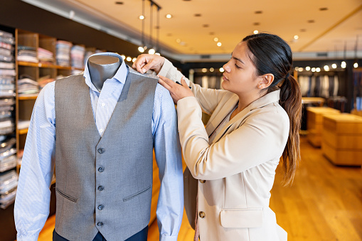 Latin American seamstress stitching clothes on a mannequin at her shop - menswear concepts