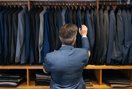 Rear view of a man looking at clothes at a clothing store - shopping concepts