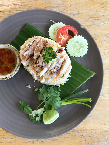 Crab fried rice with crab meat on top and beautifully arranged in a woven basket plate.