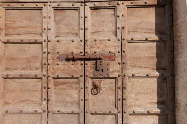 Close-up door-hardware on old wooden panelled door on street in traditional Italian town.