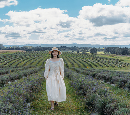 Young Asian woman standing in a picked lavender field looking into the camera